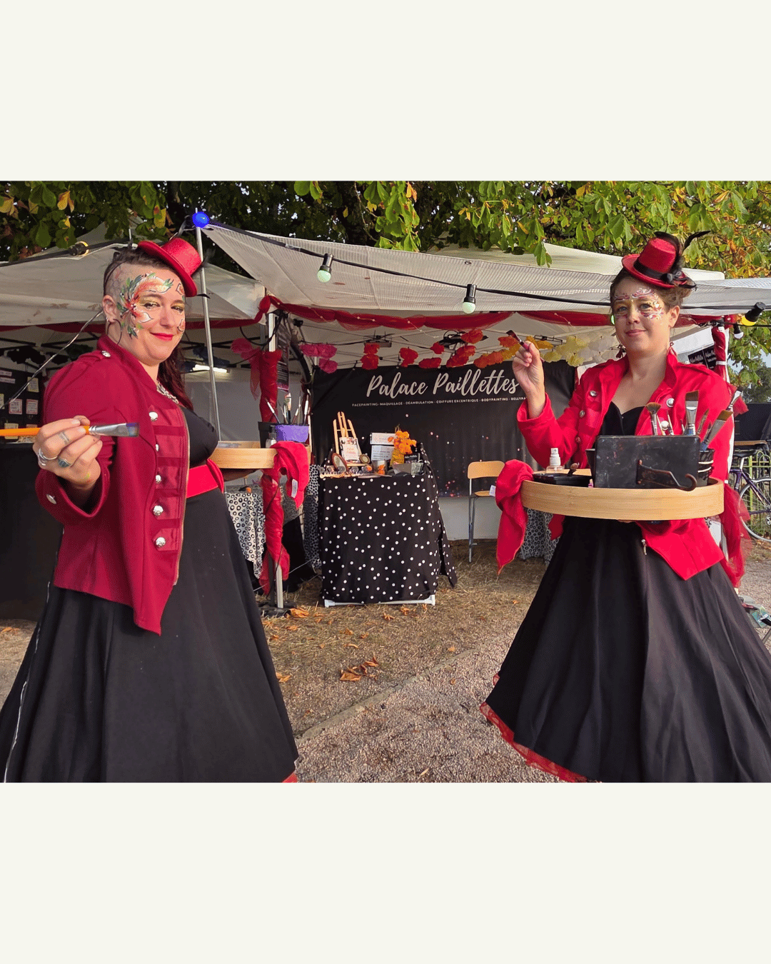 Deux maquilleuse en robe noires, veste et chapeau rouge nous font face. Elles portent des plateaux avec leur matériel et font mine de nous maquiller. Derrière elle, leur stand.